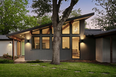 Example of a mid-sized 1960s black one-story concrete and clapboard house exterior design in Austin with a butterfly roof, a shingle roof and a black roof
