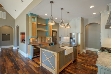 Enclosed kitchen - large transitional u-shaped medium tone wood floor and brown floor enclosed kitchen idea in Other with a farmhouse sink, shaker cabinets, white cabinets, quartzite countertops, white backsplash, subway tile backsplash, stainless steel appliances and an island