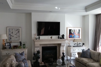 This is an example of a mid-sized traditional enclosed living room in Toronto with a wall-mounted tv, white walls, a standard fireplace and a stone fireplace surround.