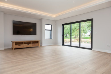 Inspiration for an open concept vinyl floor family room remodel in Other with gray walls and a wall-mounted tv