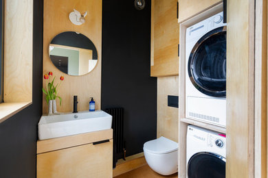 Modelo de lavadero multiusos contemporáneo pequeño con suelo de corcho, lavadora y secadora apiladas y madera