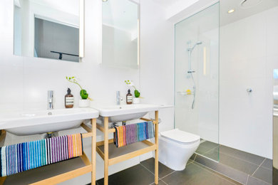Small contemporary master bathroom in Auckland with raised-panel cabinets, an alcove shower, a two-piece toilet, white tile, porcelain tile, white walls, ceramic floors and a pedestal sink.