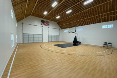 Light wood floor and vaulted ceiling indoor basketball/tennis/multi-game court photo in Other with white walls