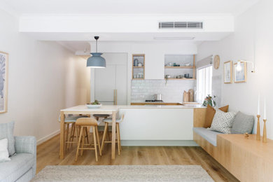 This is an example of a small modern u-shaped eat-in kitchen in Adelaide with an undermount sink, recessed-panel cabinets, light wood cabinets, laminate benchtops, yellow splashback, subway tile splashback, stainless steel appliances, medium hardwood floors, with island, brown floor and white benchtop.