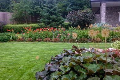 Foto de jardín campestre grande en verano en patio con parterre de flores y exposición total al sol