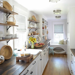 Beach style kitchen pantry designs - Example of a coastal u-shaped dark wood floor and brown floor kitchen pantry design in Charleston with a drop-in sink, recessed-panel cabinets, white cabinets, wood countertops and no island
