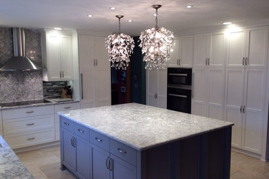 Inspiration for a mid-sized transitional l-shaped travertine floor and beige floor kitchen pantry remodel in Minneapolis with shaker cabinets, white cabinets, granite countertops, gray backsplash, ceramic backsplash, black appliances, an island and a double-bowl sink