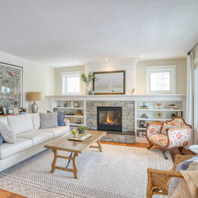 Elegant medium tone wood floor and brown floor living room photo in Calgary with beige walls, a standard fireplace and a stacked stone fireplace