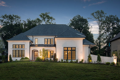 Inspiration for an eclectic white two-story brick house exterior remodel in Charlotte with a hip roof and a mixed material roof
