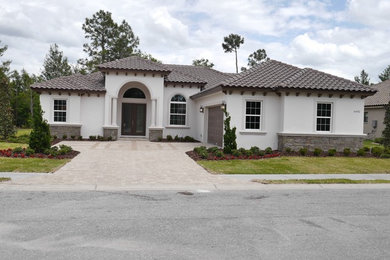 Inspiration for a mid-sized transitional beige one-story stucco house exterior remodel in Tampa with a hip roof and a tile roof