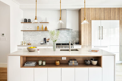 Example of a large trendy galley medium tone wood floor and brown floor eat-in kitchen design in New York with an undermount sink, flat-panel cabinets, medium tone wood cabinets, gray backsplash, stone tile backsplash, stainless steel appliances, an island, marble countertops and white countertops