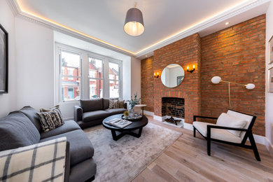 Inspiration for a medium sized living room in London with medium hardwood flooring and a brick fireplace surround.