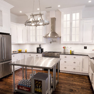 Mid-sized craftsman kitchen pantry photos - Example of a mid-sized arts and crafts u-shaped dark wood floor kitchen pantry design in Birmingham with a farmhouse sink, recessed-panel cabinets, white cabinets, granite countertops, white backsplash, porcelain backsplash, stainless steel appliances and an island