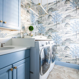 アトランタの中サイズのトラディショナルスタイルのおしゃれな洗濯室 (アンダーカウンターシンク、レイズドパネル扉のキャビネット、青いキャビネット、クオーツストーンカウンター、青い壁、磁器タイルの床、左右配置の洗濯機・乾燥機、ベージュの床、白いキッチンカウンター) の写真