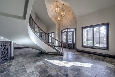 Large tuscan ceramic tile and brown floor entryway photo in Austin with beige walls and a glass front door