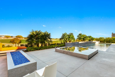 Example of a large minimalist backyard stamped concrete patio design in Las Vegas with a fire pit and no cover