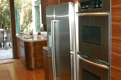 Eat-in kitchen - mid-sized modern galley bamboo floor eat-in kitchen idea in Los Angeles with a double-bowl sink, flat-panel cabinets, medium tone wood cabinets, marble countertops, glass tile backsplash, stainless steel appliances, an island and multicolored backsplash