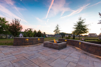 This is an example of a mid-sized modern backyard patio in Philadelphia with a fire feature, natural stone pavers and a roof extension.