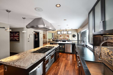 Eat-in kitchen - mid-sized modern l-shaped medium tone wood floor eat-in kitchen idea in Denver with an undermount sink, shaker cabinets, black cabinets, soapstone countertops, metallic backsplash, metal backsplash, stainless steel appliances and two islands