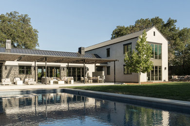 Example of a trendy white two-story stucco exterior home design in San Francisco with a metal roof and a gray roof
