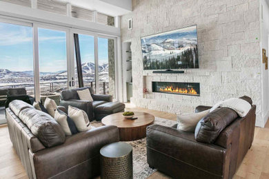 Inspiration for a large modern open concept light wood floor, brown floor and vaulted ceiling living room remodel in Salt Lake City with white walls, a ribbon fireplace, a stacked stone fireplace and a wall-mounted tv