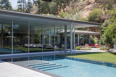 Contemporary backyard pool in Los Angeles with a pool house and concrete slab.