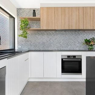 Design ideas for a contemporary l-shaped kitchen in Canberra - Queanbeyan with a drop-in sink, flat-panel cabinets, white cabinets, grey splashback, stainless steel appliances, with island, grey floor and grey benchtop.