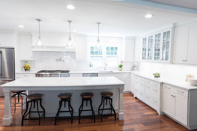Design ideas for a large transitional l-shaped eat-in kitchen in Philadelphia with an undermount sink, shaker cabinets, white cabinets, marble benchtops, white splashback, subway tile splashback, stainless steel appliances, medium hardwood floors, with island and brown floor.