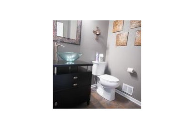 Small transitional 3/4 ceramic tile bathroom photo in Kansas City with flat-panel cabinets, dark wood cabinets, glass countertops, a two-piece toilet, a vessel sink and gray walls