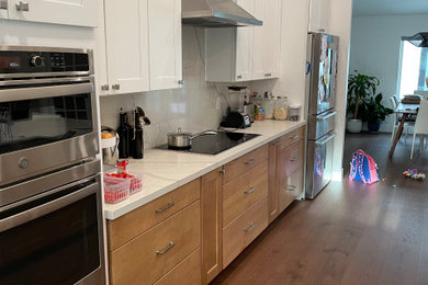 Example of a mid-sized transitional single-wall vinyl floor and brown floor open concept kitchen design in Phoenix with shaker cabinets, white cabinets, an island, an undermount sink, quartz countertops, white backsplash, quartz backsplash, stainless steel appliances and white countertops