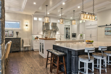 Open concept kitchen - mid-sized medium tone wood floor and brown floor open concept kitchen idea in Miami with a single-bowl sink, white cabinets, granite countertops, white backsplash, glass tile backsplash, stainless steel appliances and two islands