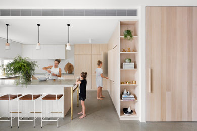 Design ideas for a large contemporary u-shaped kitchen in Melbourne with an undermount sink, light wood cabinets, concrete benchtops, white splashback, brick splashback, stainless steel appliances, concrete floors and no island.