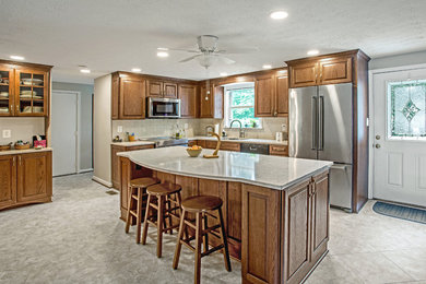 Kitchen pantry - mid-sized traditional l-shaped vinyl floor and gray floor kitchen pantry idea in DC Metro with an undermount sink, raised-panel cabinets, medium tone wood cabinets, quartz countertops, white backsplash, porcelain backsplash, stainless steel appliances, an island and white countertops