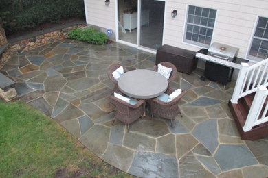 Example of a mid-sized classic backyard stone patio kitchen design in New York with no cover