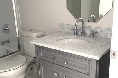 Example of a small transitional gray tile porcelain tile and white floor bathroom design in Miami with shaker cabinets, gray cabinets, a two-piece toilet, gray walls, an undermount sink and marble countertops