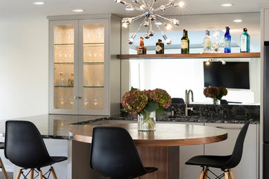 Mid-sized transitional galley seated home bar in Minneapolis with an undermount sink, glass-front cabinets, white cabinets, wood benchtops, mirror splashback, dark hardwood floors and brown floor.