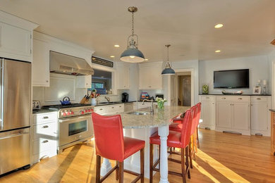 Large elegant l-shaped medium tone wood floor and brown floor eat-in kitchen photo in New York with an undermount sink, beaded inset cabinets, white cabinets, granite countertops, white backsplash, subway tile backsplash, stainless steel appliances and an island