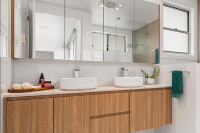 Inspiration for a mid-sized beach style bathroom in Newcastle - Maitland with furniture-like cabinets, light wood cabinets, a curbless shower, white tile, ceramic tile, engineered quartz benchtops, grey benchtops, a double vanity and a floating vanity.