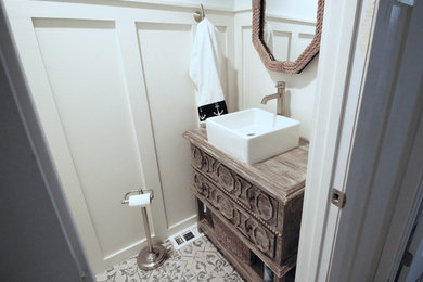 Small beach style beige floor powder room photo in Austin with furniture-like cabinets, medium tone wood cabinets, white walls, a vessel sink, wood countertops and brown countertops