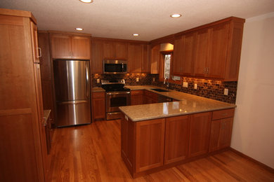Mid-sized elegant u-shaped medium tone wood floor open concept kitchen photo in Minneapolis with an undermount sink, shaker cabinets, red cabinets, quartz countertops, brown backsplash, stone tile backsplash, stainless steel appliances and a peninsula