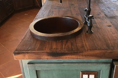 Inspiration for a mid-sized southwestern terra-cotta tile eat-in kitchen remodel in Phoenix with a drop-in sink, recessed-panel cabinets, distressed cabinets, wood countertops, stainless steel appliances and an island