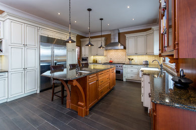 Large elegant u-shaped dark wood floor eat-in kitchen photo in Toronto with a farmhouse sink, raised-panel cabinets, stainless steel appliances, an island, beige cabinets, granite countertops, beige backsplash and stone tile backsplash