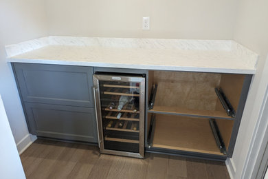 Example of a small galley laminate floor and brown floor dry bar design in Other with flat-panel cabinets, gray cabinets, solid surface countertops, multicolored backsplash and multicolored countertops