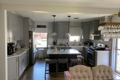Example of a mid-sized transitional l-shaped dark wood floor and brown floor eat-in kitchen design in Other with a farmhouse sink, shaker cabinets, gray cabinets, quartz countertops, white backsplash, subway tile backsplash, stainless steel appliances, an island and white countertops
