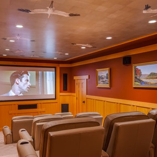 This is an example of a medium sized traditional enclosed home cinema in Portland Maine with red walls, carpet, a projector screen and beige floors.