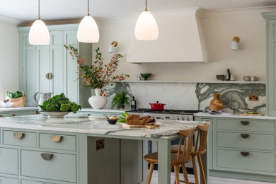 Inspiration for a large traditional l-shaped kitchen/diner in Surrey with a belfast sink, shaker cabinets, green cabinets, marble worktops, multi-coloured splashback, marble splashback, laminate floors, an island, brown floors, multicoloured worktops and a chimney breast.