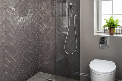 This is an example of a mid-sized contemporary bathroom in London with an open shower, a one-piece toilet, gray tile, ceramic tile, grey walls, porcelain floors, grey floor and a hinged shower door.