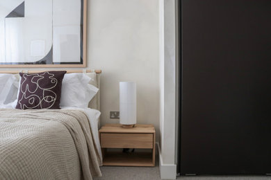This is an example of a medium sized scandi master bedroom in London with beige walls, carpet and beige floors.