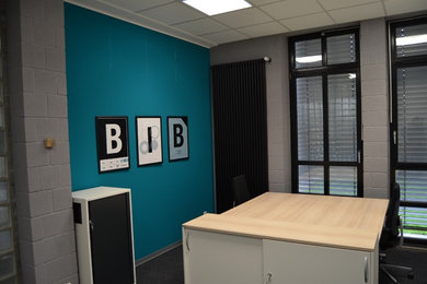Immagine di un ampio ufficio contemporaneo con pareti verdi, moquette, scrivania autoportante e pavimento grigio