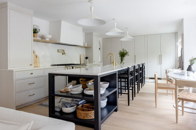 Enclosed kitchen - mid-sized scandinavian l-shaped light wood floor and brown floor enclosed kitchen idea in Vancouver with a farmhouse sink, flat-panel cabinets, white cabinets, white backsplash, an island and white countertops